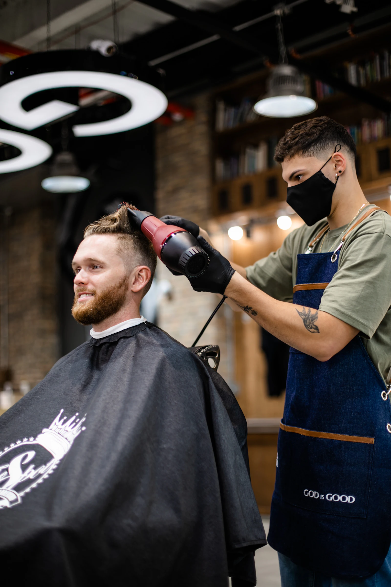 A barber blow-drying a client's hair