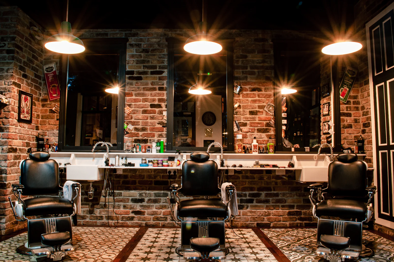 Barber chairs under warm pendant lights against a brick wall